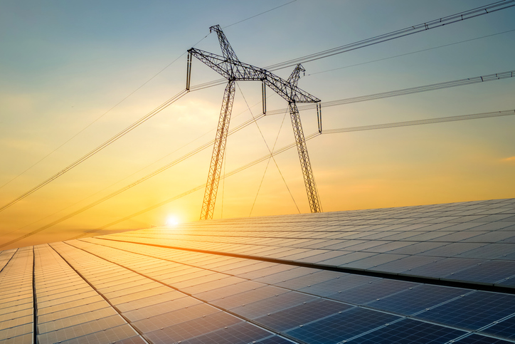 Højspændingsmaster med elledninger, der overfører elektricitet fra solceller ved solopgang.